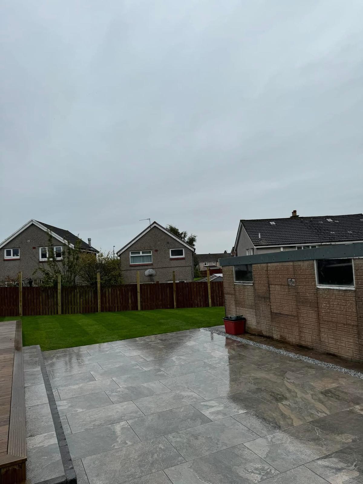 Fresh turf rolls being laid on prepared soil in a Glasgow residential garden by Oaklands Treecare
